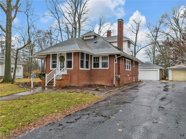 bungalow-style house with an outbuilding, a garage, and a front lawn