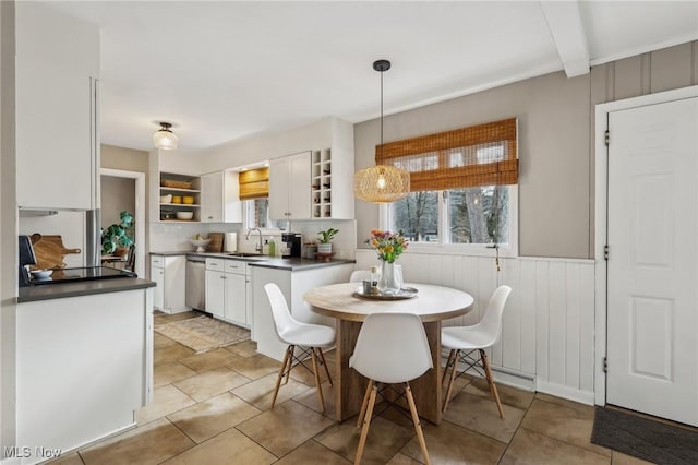 tiled dining space featuring a baseboard radiator, sink, and beam ceiling