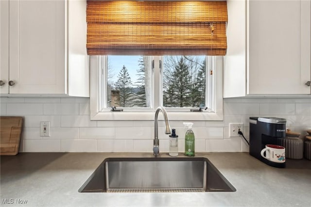 kitchen with tasteful backsplash, sink, and white cabinets