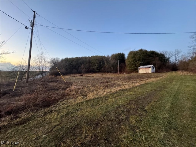 yard at dusk featuring a storage unit and a rural view