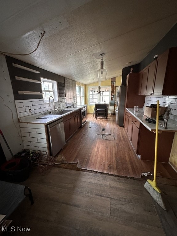 kitchen with sink, vaulted ceiling, appliances with stainless steel finishes, dark hardwood / wood-style floors, and backsplash