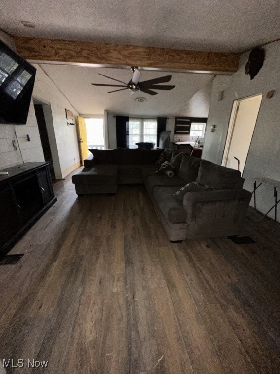 unfurnished living room with dark wood-type flooring, ceiling fan, lofted ceiling with beams, and a textured ceiling