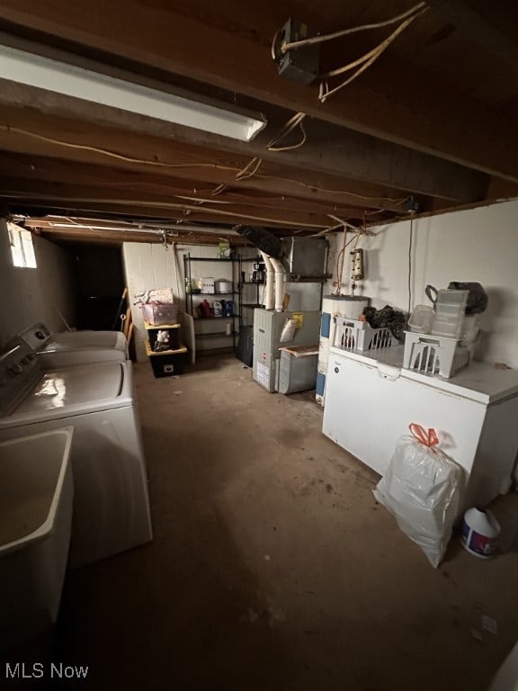 basement with water heater, heating unit, and washer and dryer