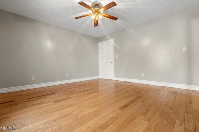 empty room with light wood finished floors, a ceiling fan, and baseboards