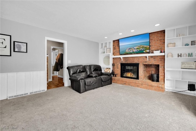 carpeted living room with a brick fireplace and built in features