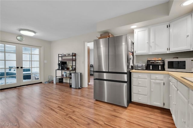 kitchen featuring white cabinetry, stainless steel fridge, light wood-type flooring, and french doors