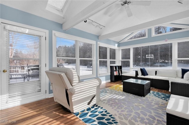 sunroom featuring vaulted ceiling with skylight, track lighting, and ceiling fan