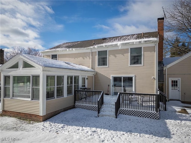 snow covered rear of property with a deck