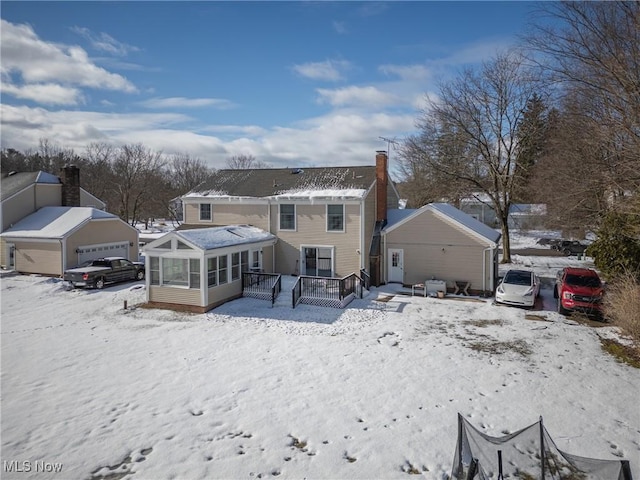 snow covered house featuring a deck and a sunroom