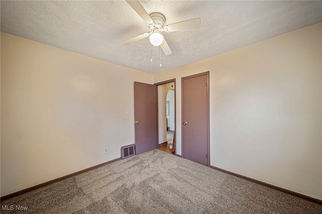 empty room with ceiling fan, carpet flooring, and a textured ceiling