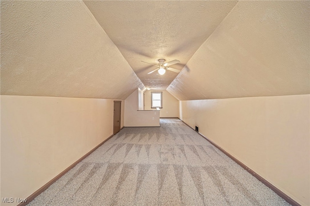 bonus room featuring ceiling fan, lofted ceiling, light carpet, and a textured ceiling