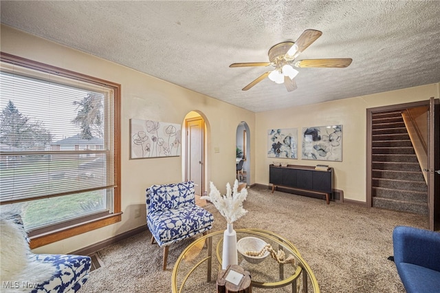 carpeted living room with ceiling fan and a textured ceiling