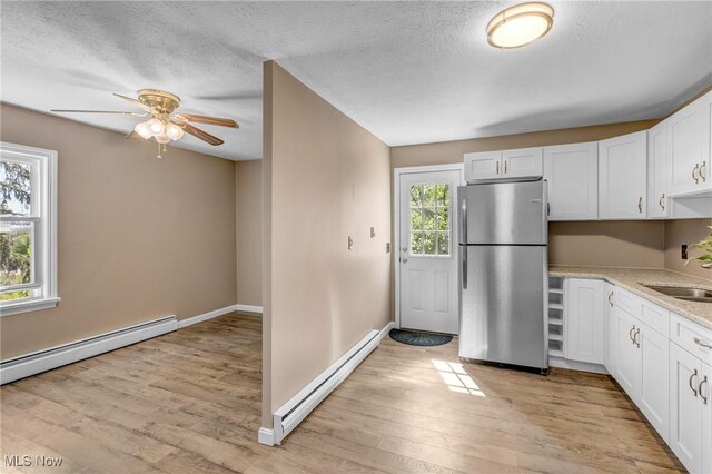 24512 Emery Rd, Warrensville Heights, OH 44128 - kitchen with white cabinetry, stainless steel fridge, baseboard heating, and light hardwood / wood-style floors
