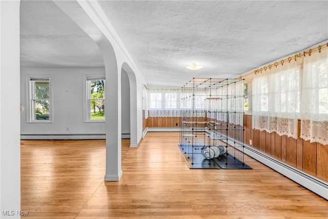 24512 Emery Rd, Warrensville Heights, OH 44128 - exercise area with baseboard heating, a textured ceiling, and light wood-type flooring