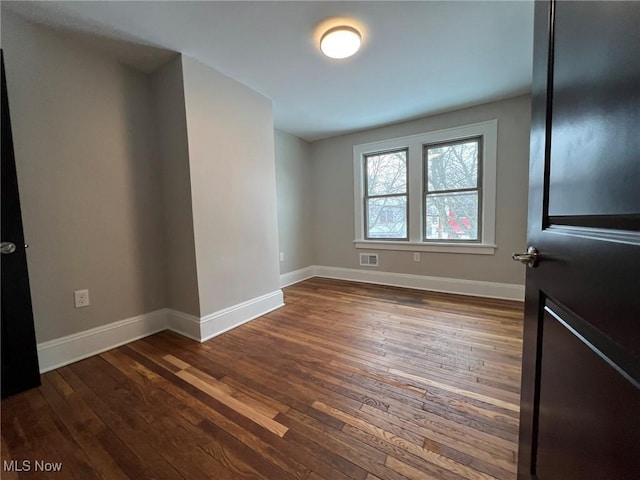 unfurnished room with dark wood-type flooring