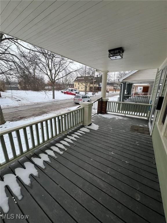 snow covered deck featuring a porch