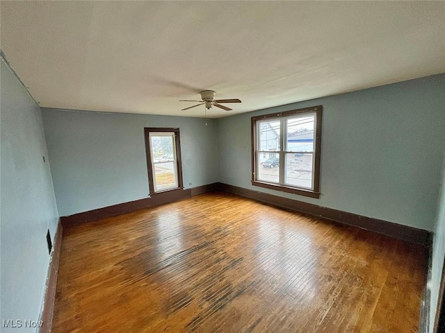 empty room featuring ceiling fan, wood-type flooring, and a wealth of natural light