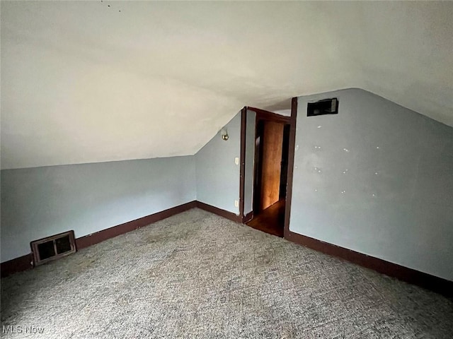 additional living space with vaulted ceiling and carpet flooring