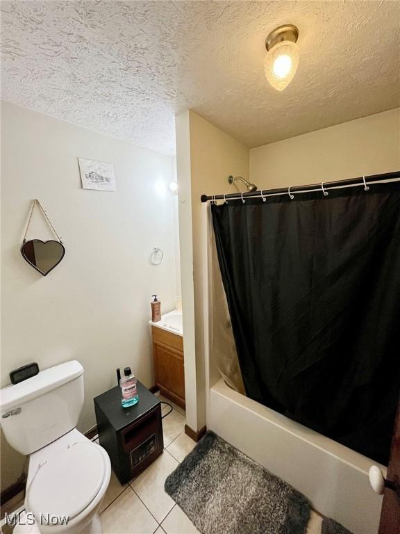 full bathroom featuring vanity, toilet, shower / bath combo, tile patterned floors, and a textured ceiling