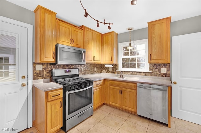 kitchen featuring sink, decorative light fixtures, backsplash, and appliances with stainless steel finishes