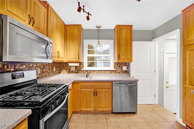 kitchen featuring sink, hanging light fixtures, light tile patterned floors, appliances with stainless steel finishes, and backsplash