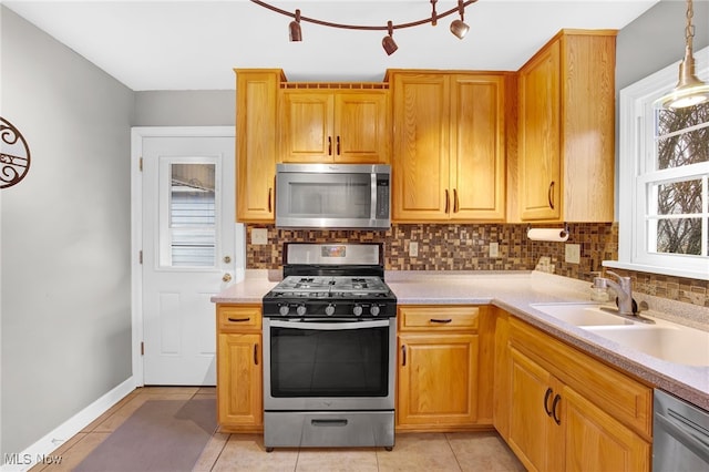 kitchen with light tile patterned flooring, appliances with stainless steel finishes, pendant lighting, tasteful backsplash, and sink