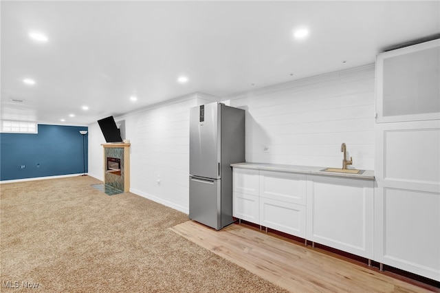 basement featuring a tile fireplace, sink, light carpet, and stainless steel fridge