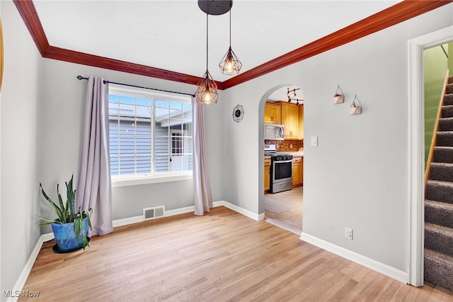 unfurnished dining area with ornamental molding and light wood-type flooring