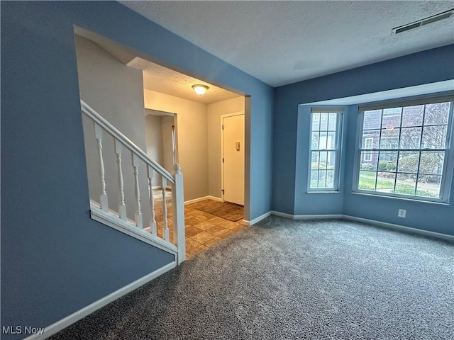 carpeted spare room featuring a textured ceiling