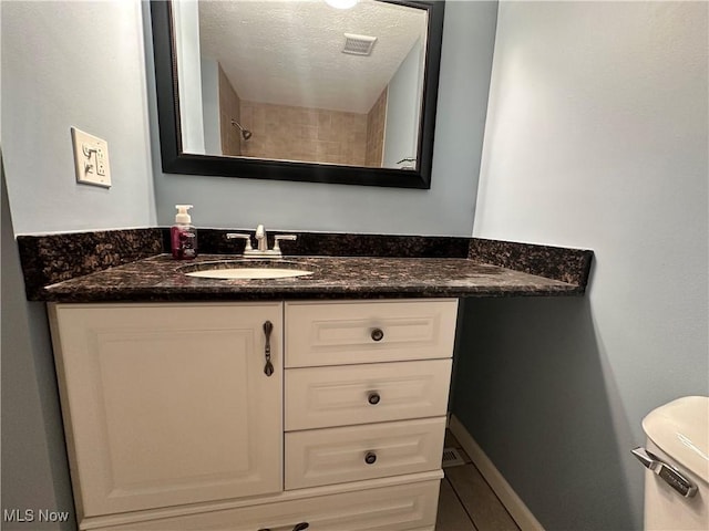 bathroom featuring vanity, toilet, and a textured ceiling