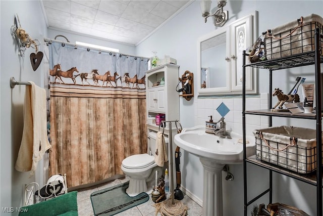 bathroom featuring a shower with shower curtain, ornamental molding, toilet, and sink