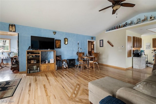 living room with lofted ceiling, ceiling fan, and light wood-type flooring