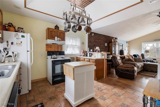 kitchen featuring ceiling fan with notable chandelier, dishwasher, white refrigerator, a center island, and electric stove