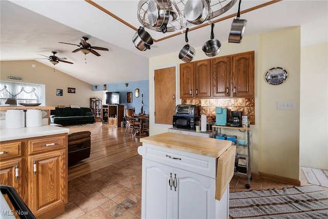 kitchen featuring wooden counters, ceiling fan, white cabinets, decorative backsplash, and vaulted ceiling