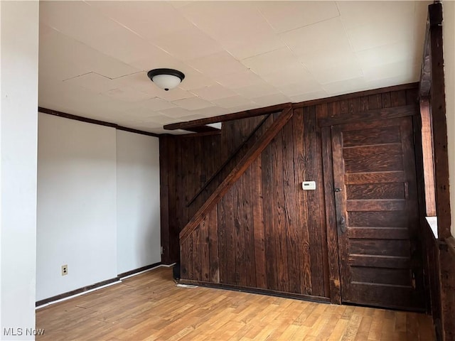 basement with light wood-type flooring and wood walls