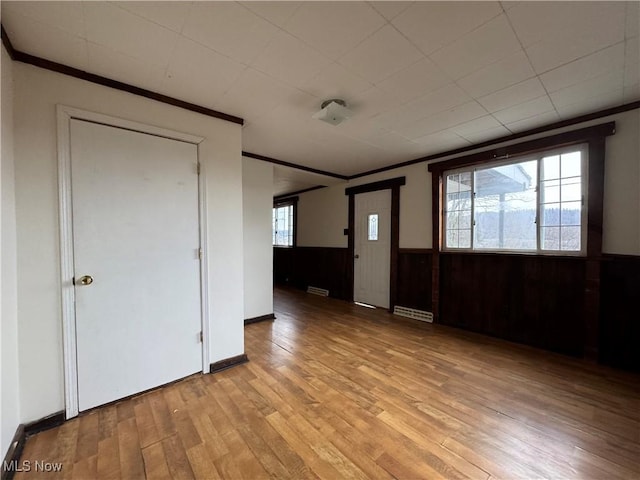 interior space with a baseboard heating unit, ornamental molding, and light hardwood / wood-style floors