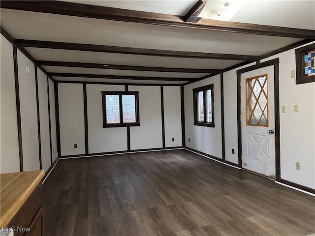 interior space with dark hardwood / wood-style flooring and beamed ceiling