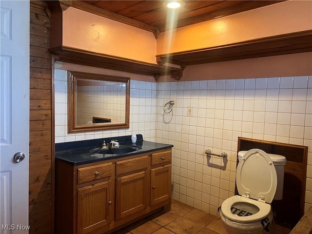 bathroom featuring vanity, tile patterned flooring, toilet, and tile walls