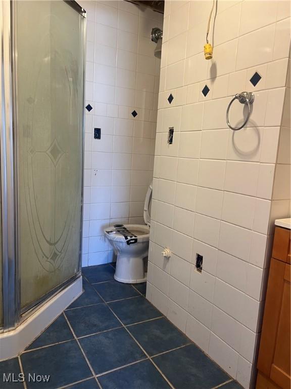 bathroom featuring walk in shower, tile patterned floors, toilet, tile walls, and vanity