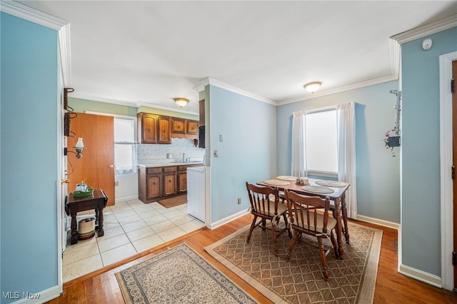 dining room with sink, crown molding, and light hardwood / wood-style floors