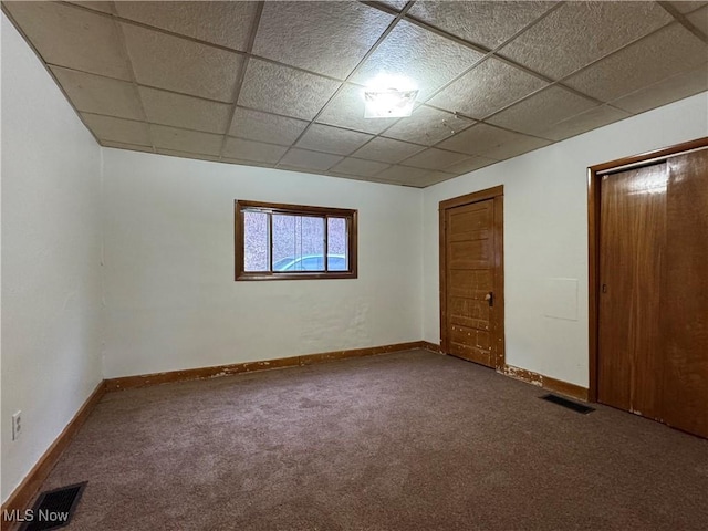 spare room featuring carpet and a drop ceiling