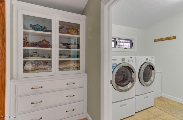 clothes washing area with washer and clothes dryer and light tile patterned floors