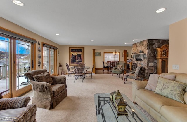 carpeted living room with a fireplace and a chandelier