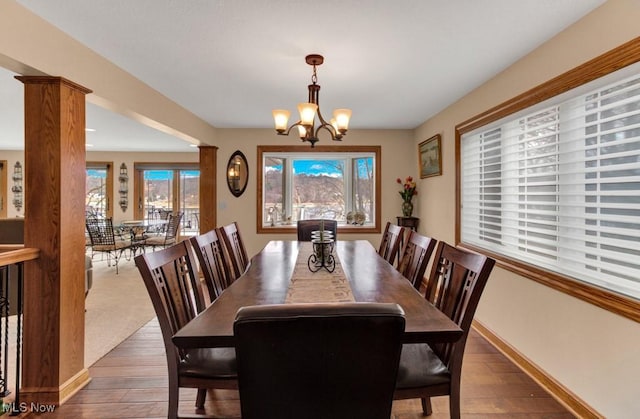 dining space with an inviting chandelier, dark hardwood / wood-style floors, and ornate columns