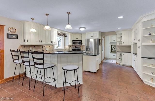 kitchen featuring appliances with stainless steel finishes, a breakfast bar, pendant lighting, white cabinets, and kitchen peninsula