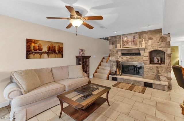 tiled living room with ceiling fan and a fireplace