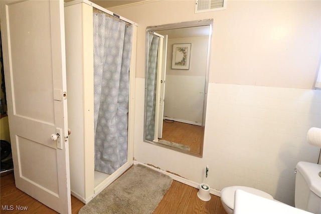 bathroom featuring wood-type flooring, toilet, and walk in shower