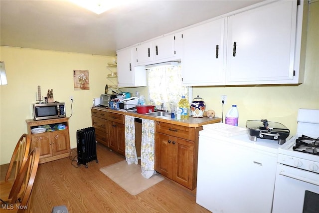 kitchen featuring white cabinetry, sink, white gas stove, and light hardwood / wood-style flooring