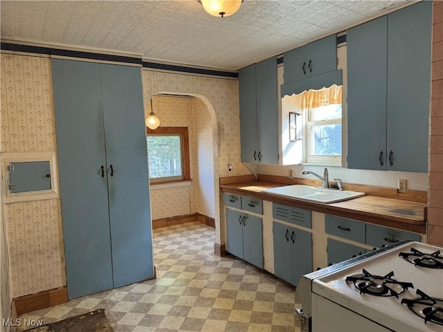 kitchen featuring pendant lighting, wood counters, white gas range, sink, and ornamental molding