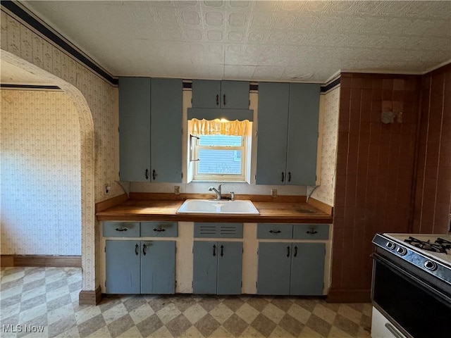 kitchen with gray cabinets, butcher block counters, sink, and white range with gas stovetop